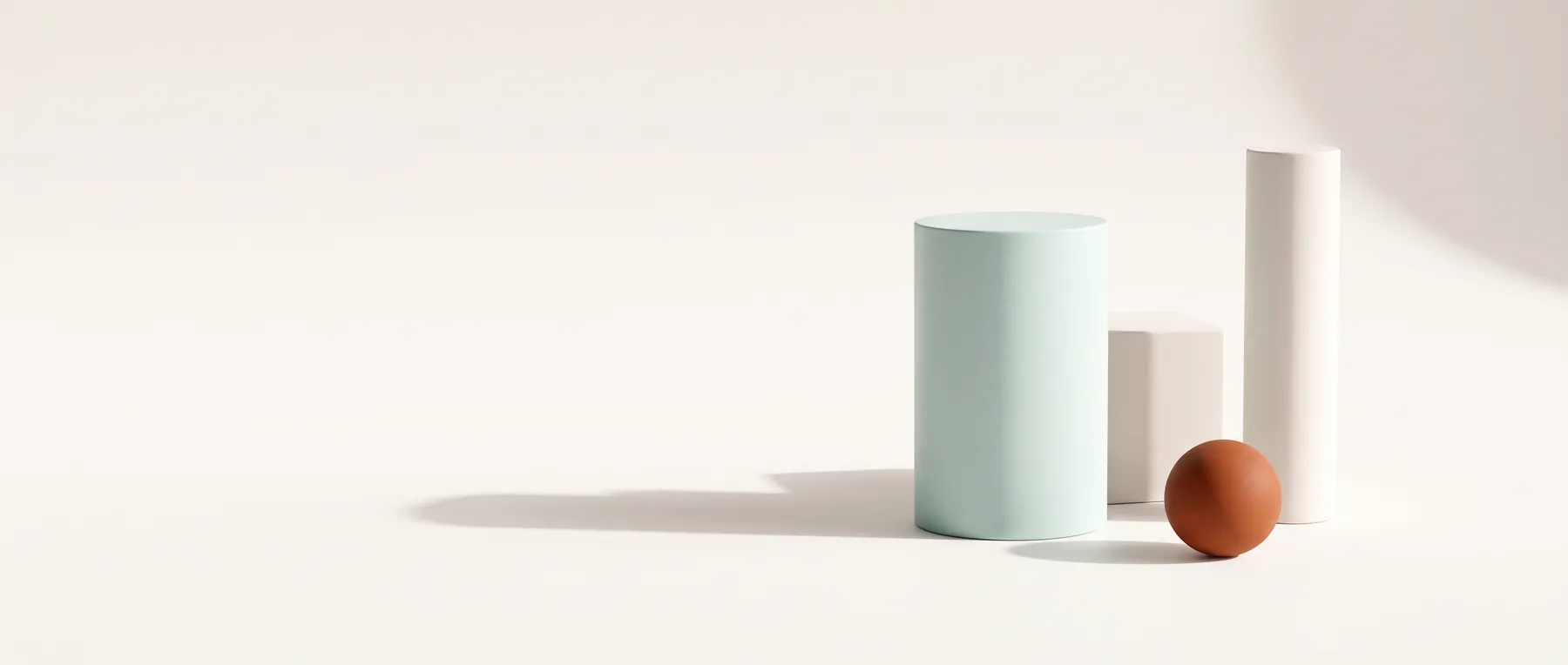 Matte geometric forms with long raking shadows and one rust sphere