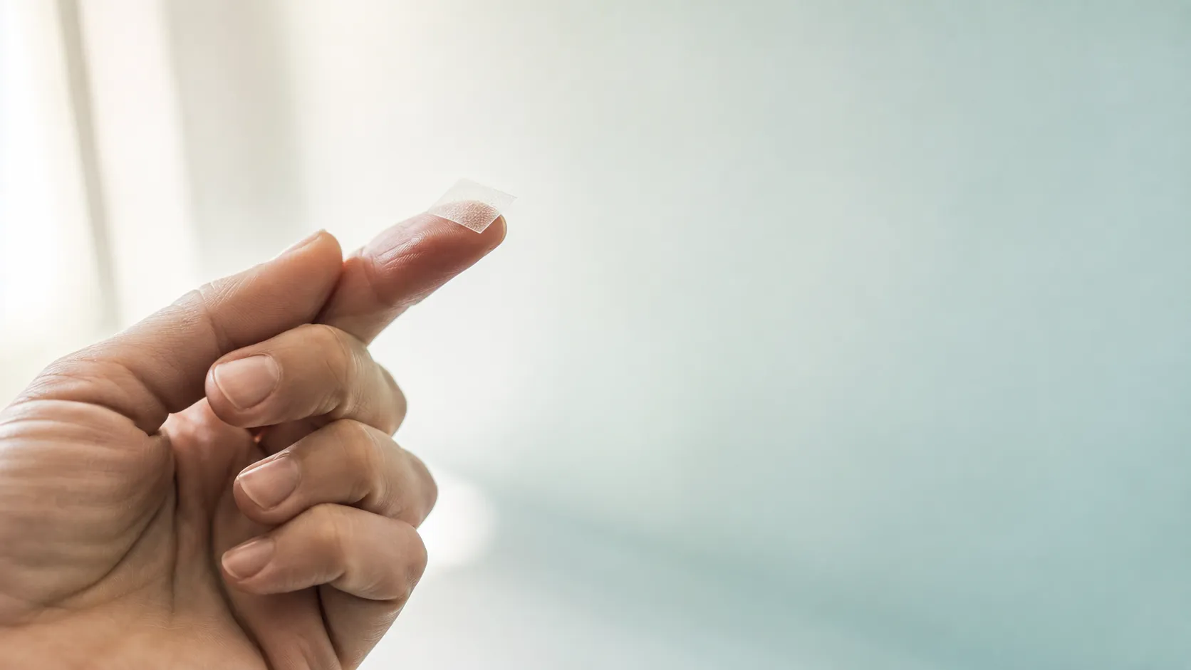 A single translucent dissolving strip resting on a fingertip in soft daylight