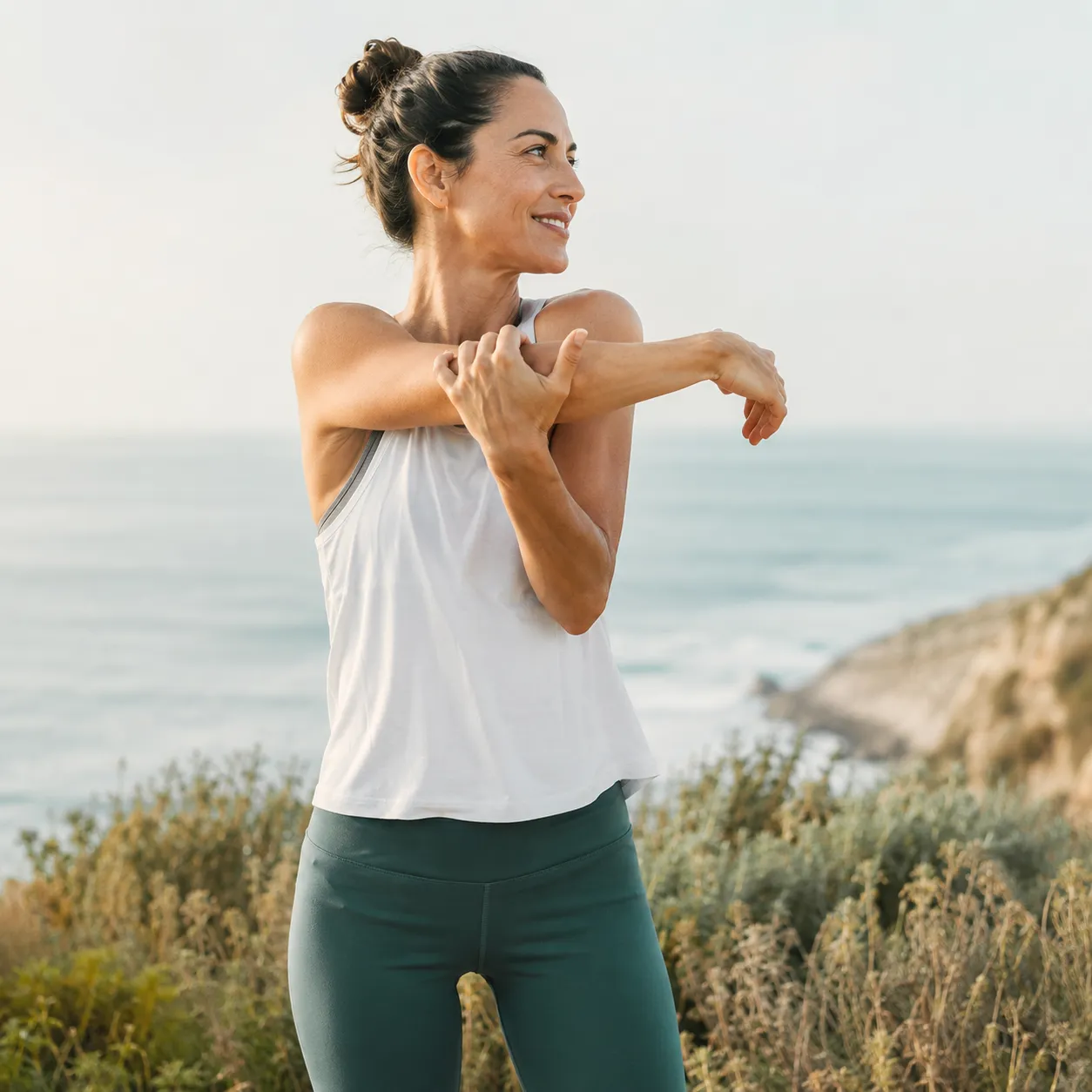 Woman stretching outdoors by the coast in soft daylight
